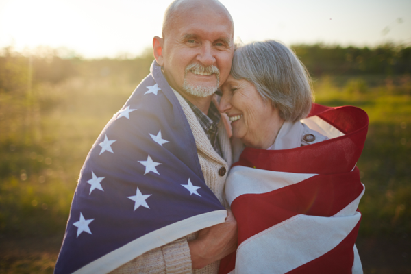 Elderly couple smiling while holding a flag of the United States