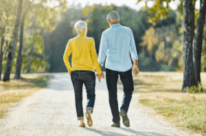 An elderly couple walking away holding hands.