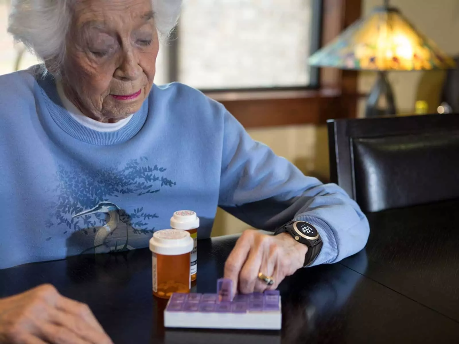 Elderly Lady with medication bottles on the table in front of her